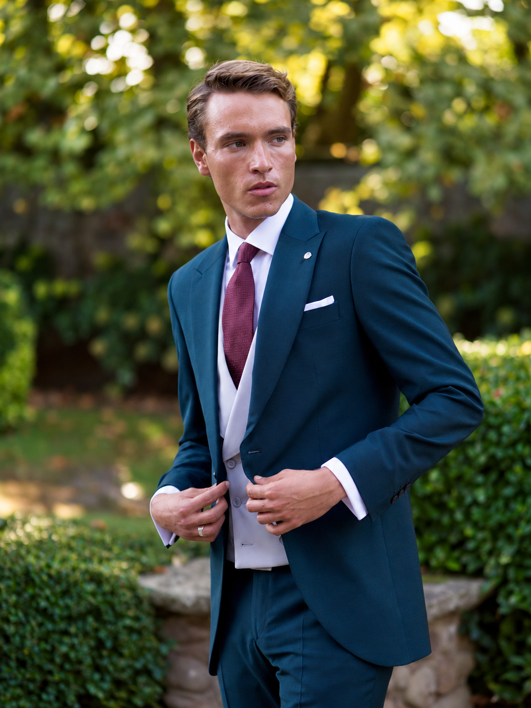 Look de novio con traje azul petróleo y corbata burdeos